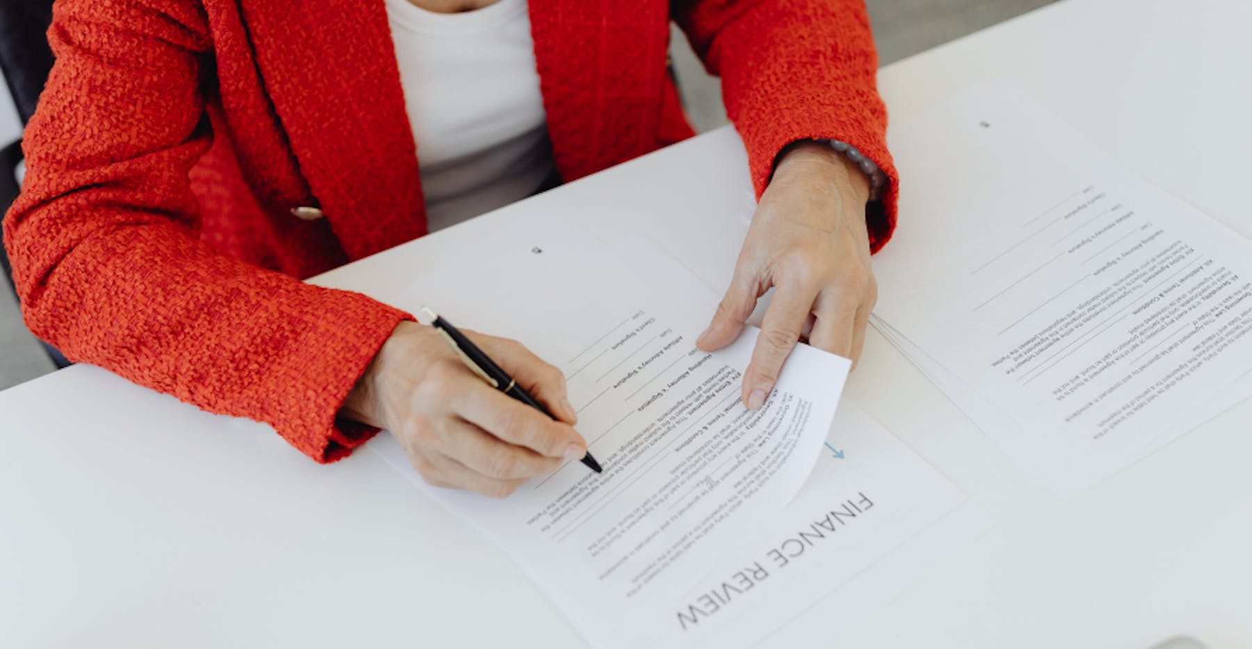 woman signing papers in red sweater