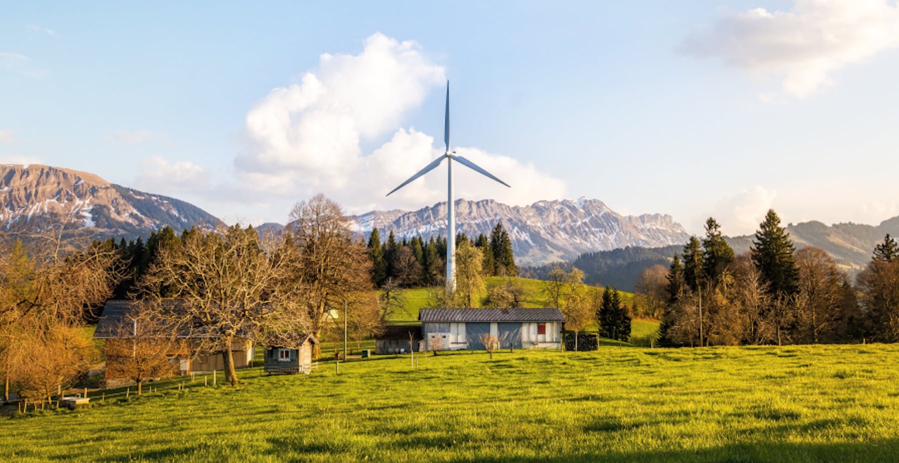 house in the countryside with a wind turbine behind it