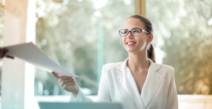 woman in office wear handing someone a report