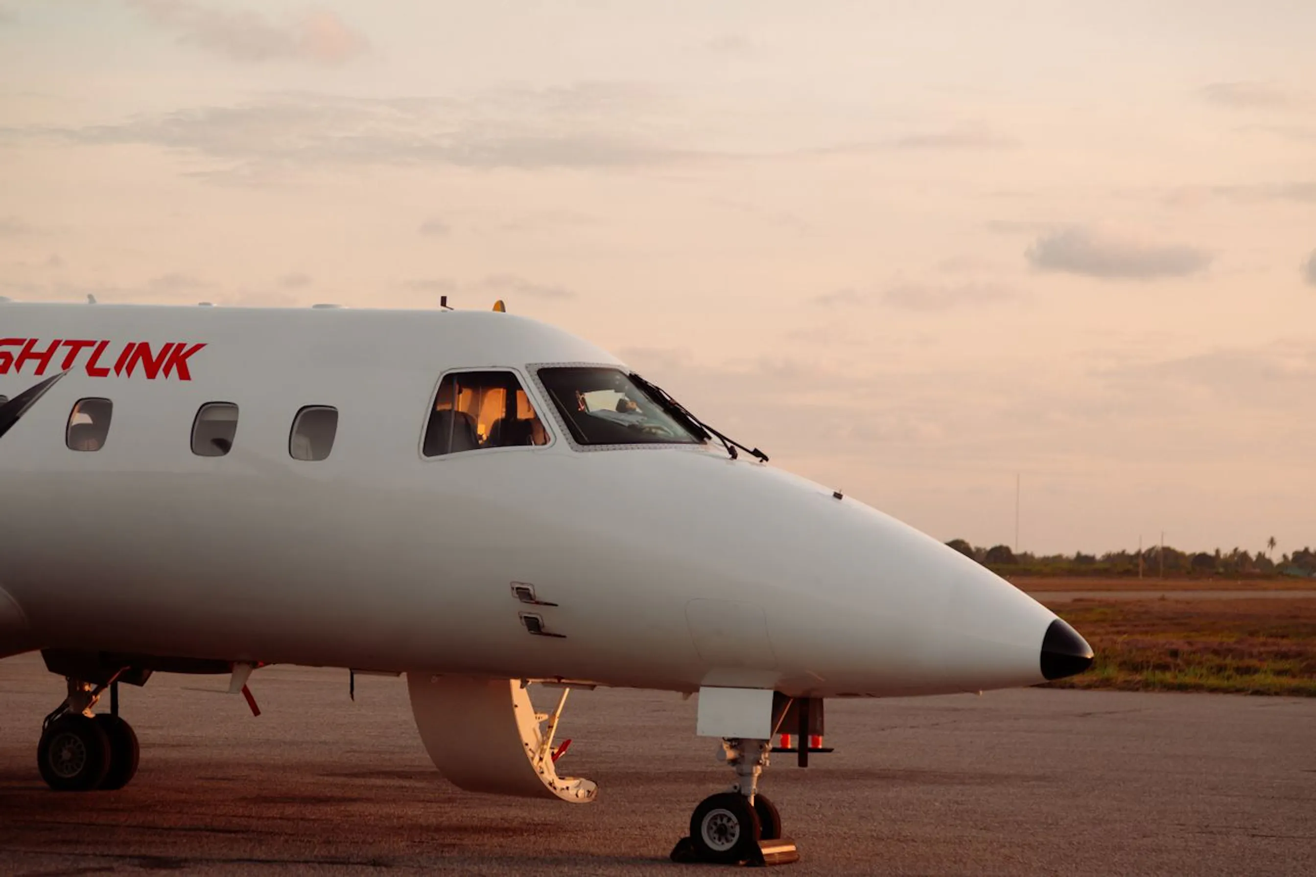 Avion privé stationné sur un tarmac au coucher du soleil.