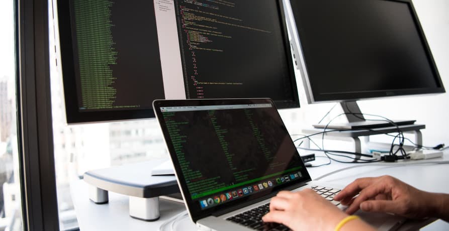 person sitting in front of computer screens