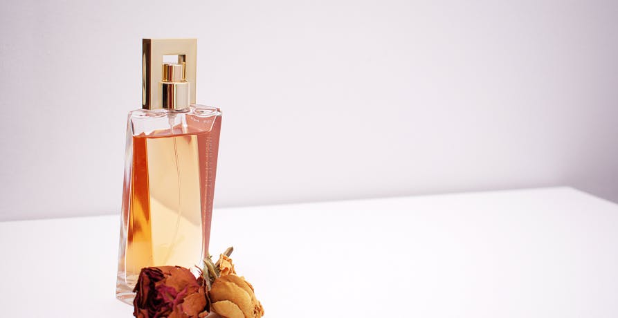 perfume on white desk with flowers