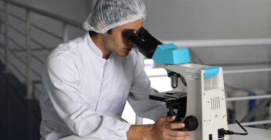 scientist in lab looking through microscope