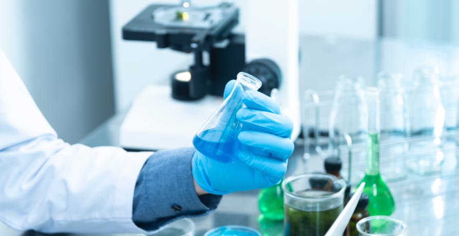 scientist holding beaker with chemicals inside