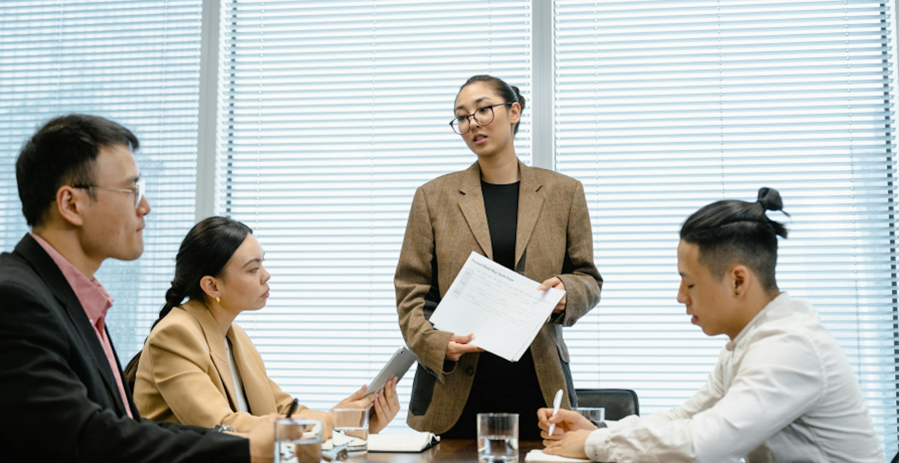 femme qui présente un document à trois autres personnes