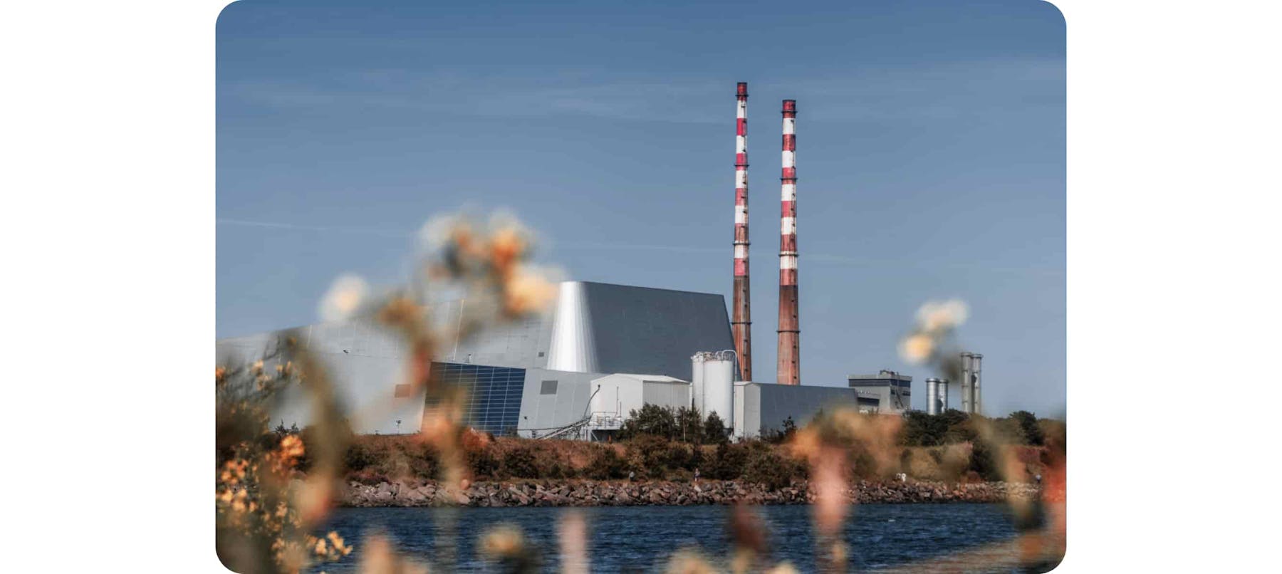 red and white factory pipe near body of water