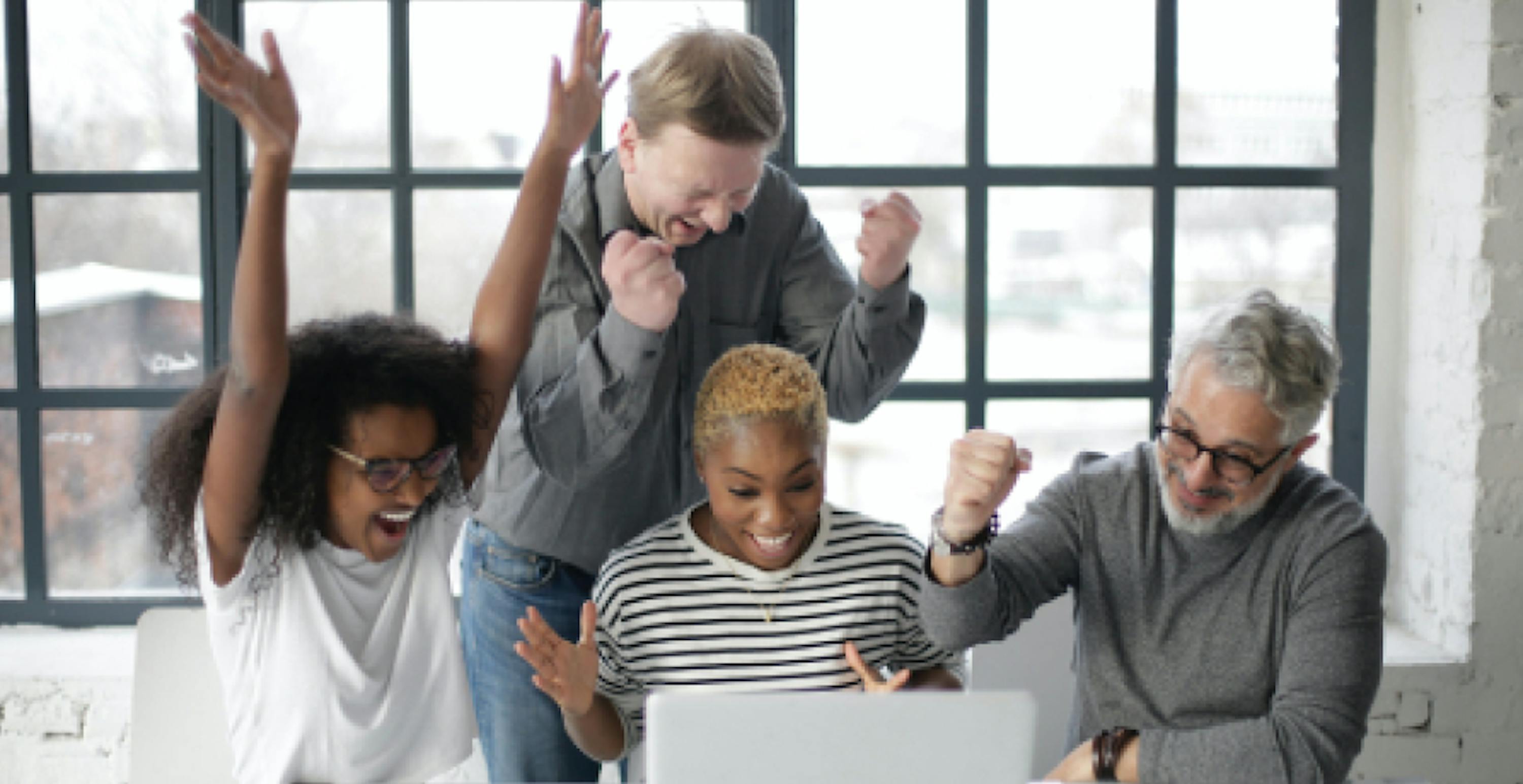 quatre personnes montrant leur joie devant un ordinateur