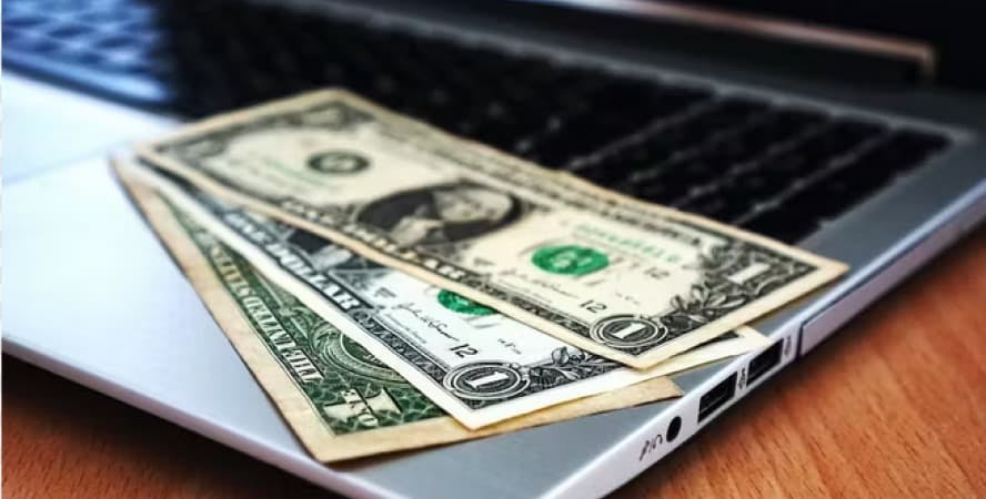USD dollar bills on laptop