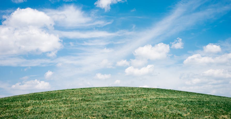 blue cloudy sky with green fields