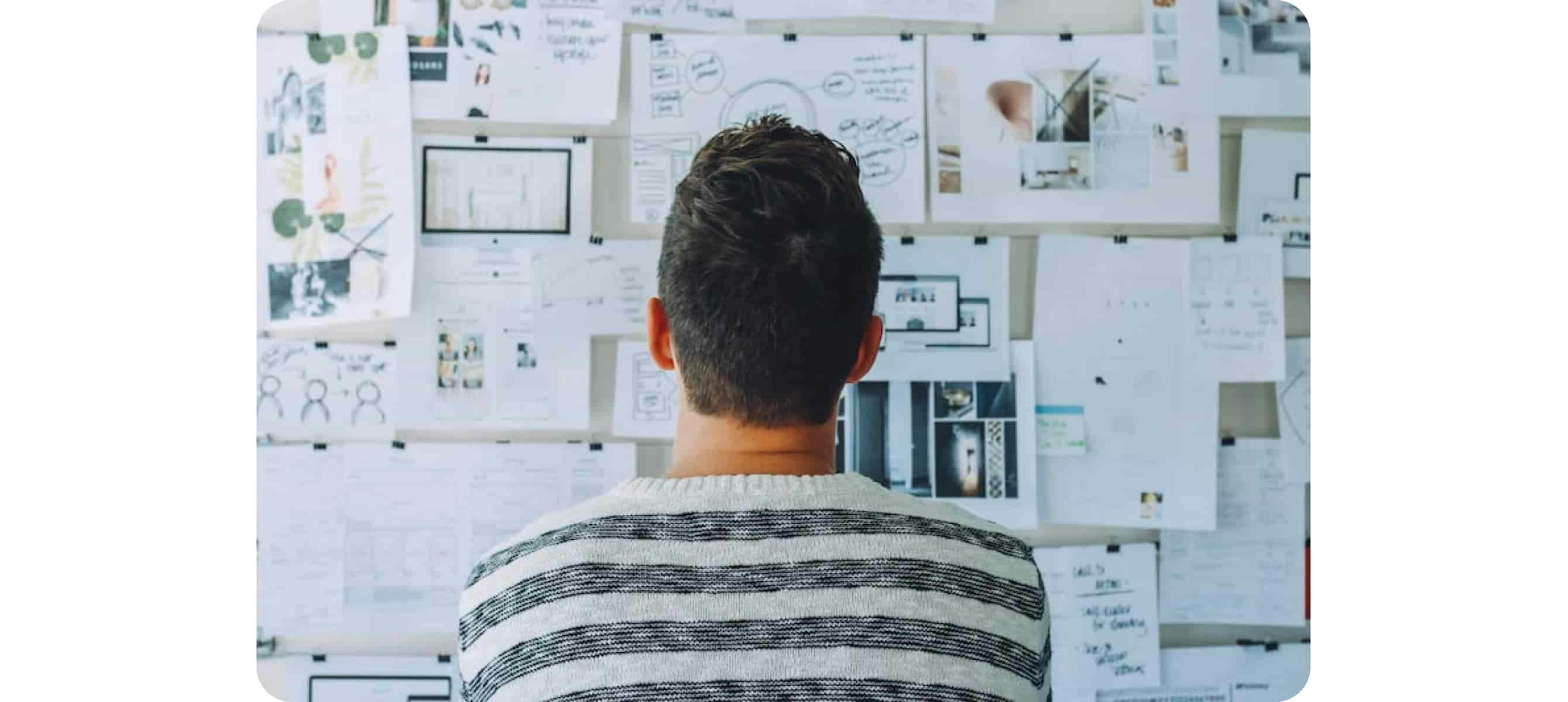 Un homme regarde un tableau avec plein de notes