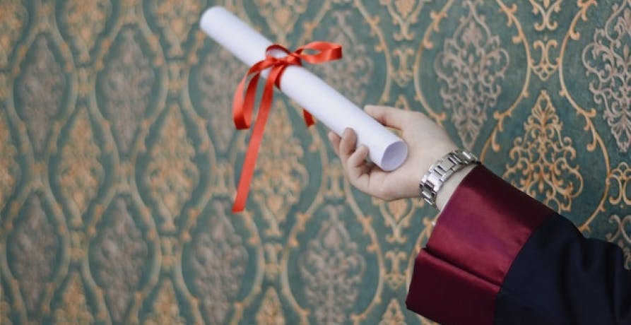 person holding a diploma with red ribbon