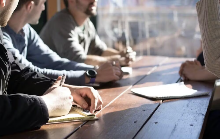 Personnes prenant des notes autour d'une table