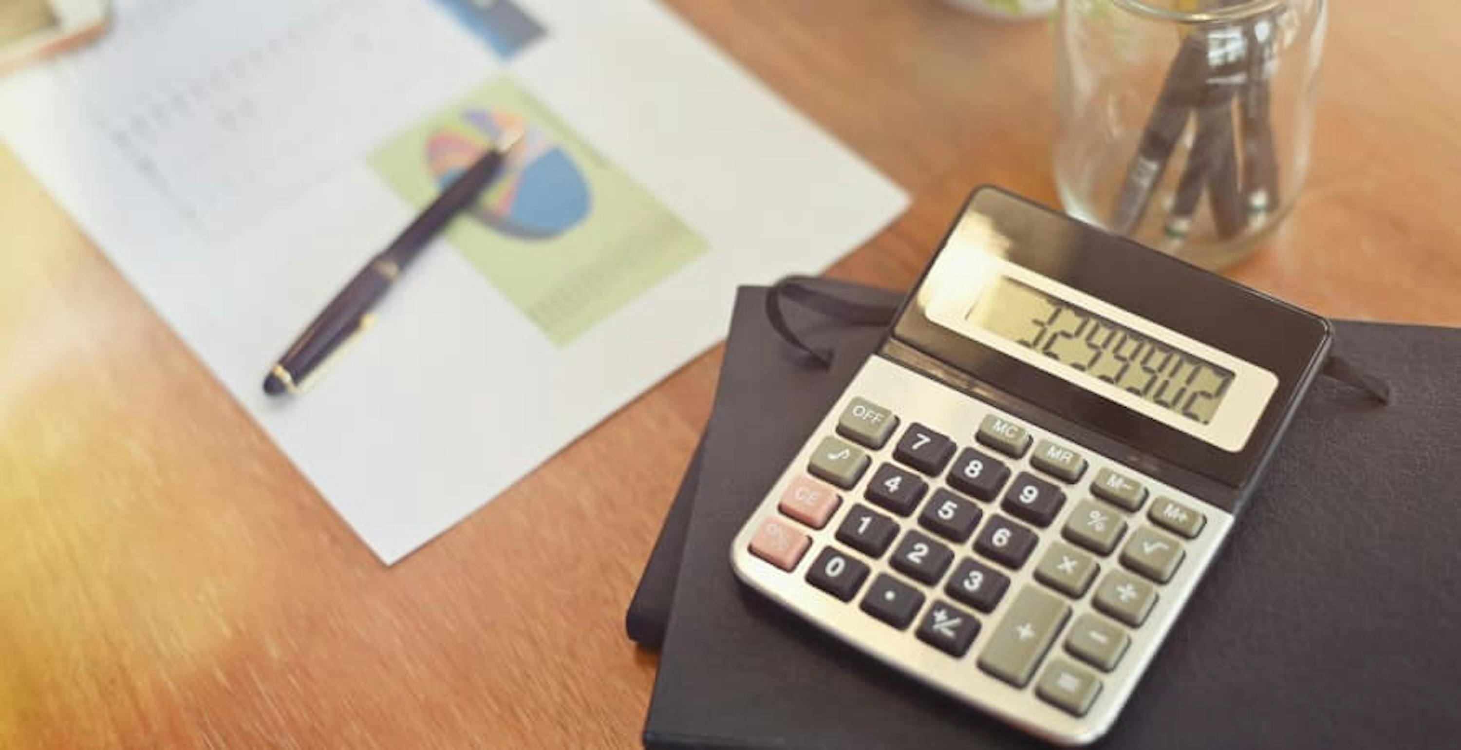 calculator and pencil on brown table