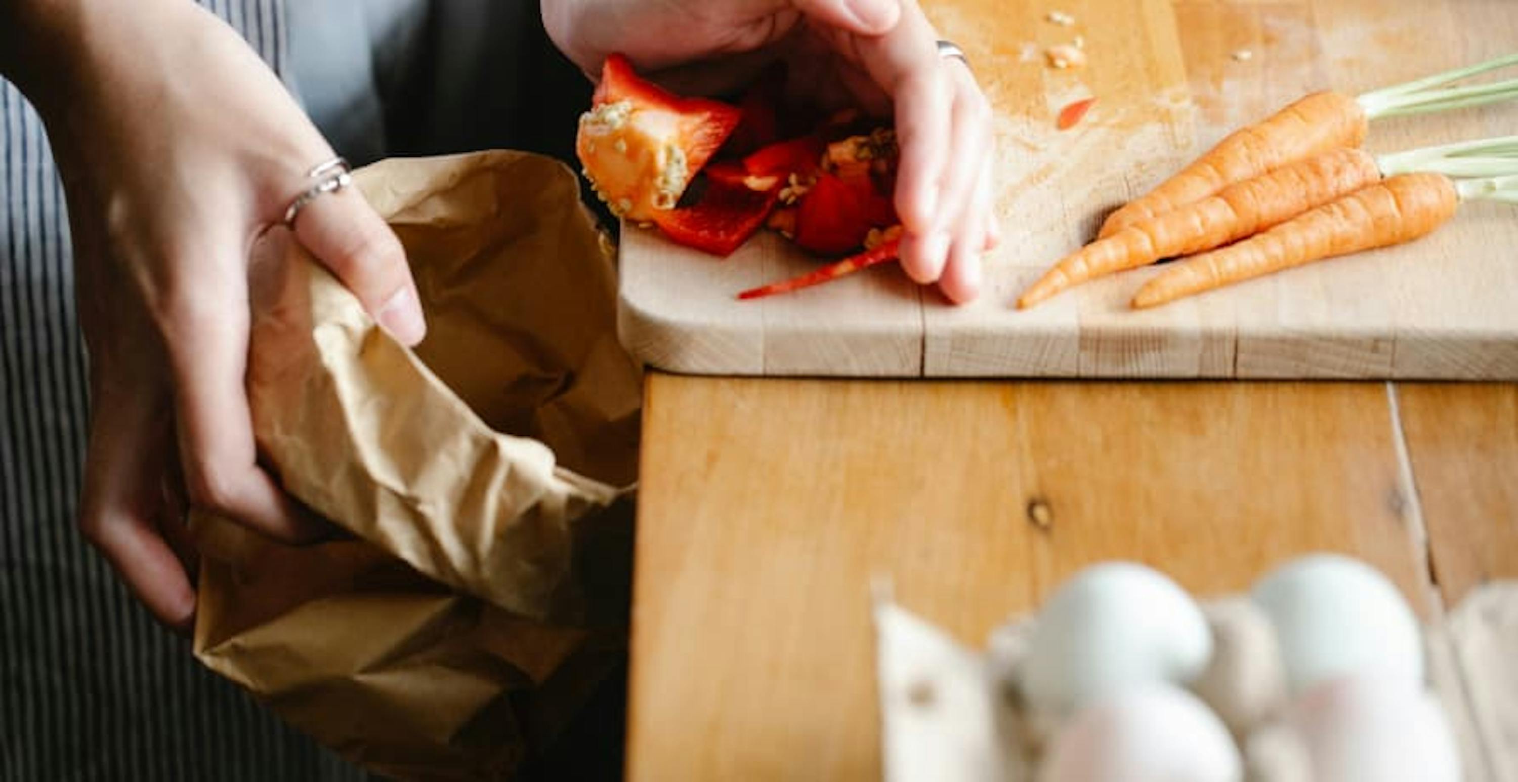 person sweeping food waste into a bag 