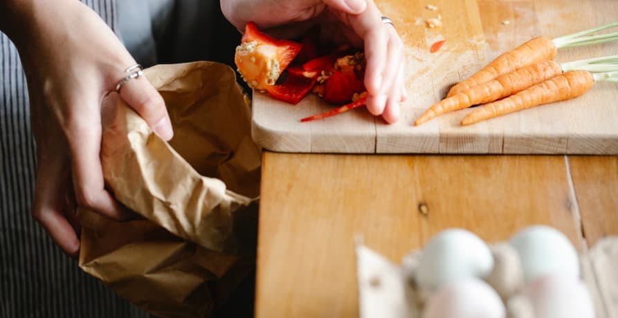 person sweeping food waste into a bag