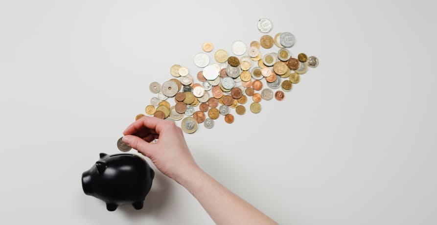woman placing coins into a piggy bank