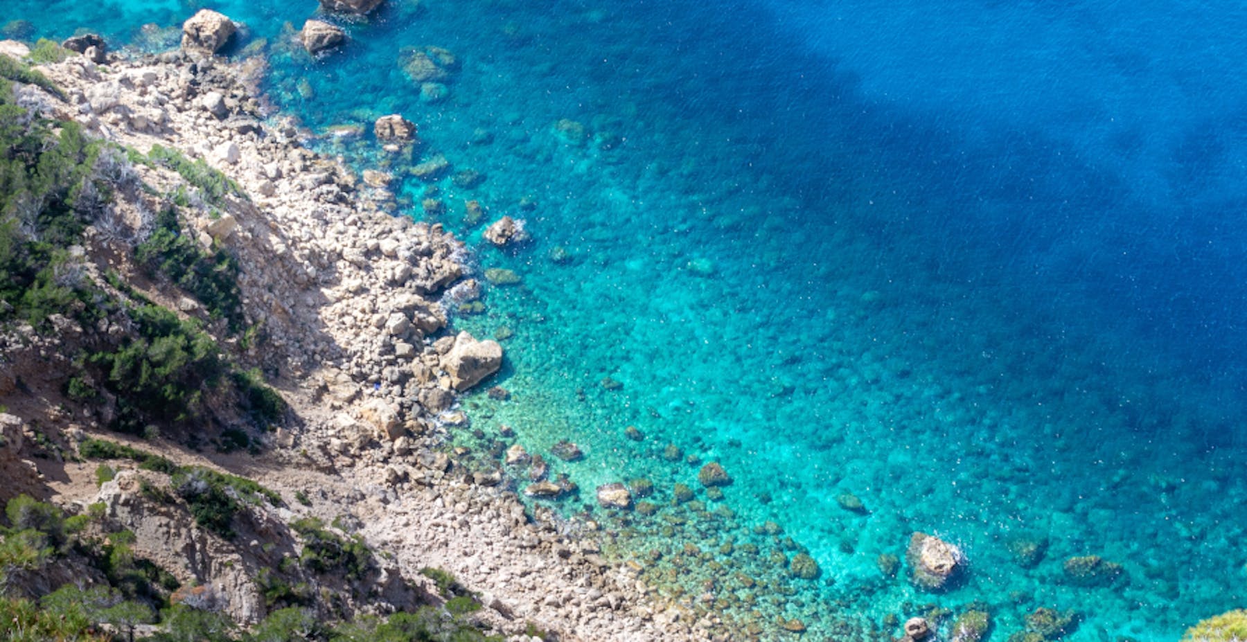 plage de galets devant une eau turquoise