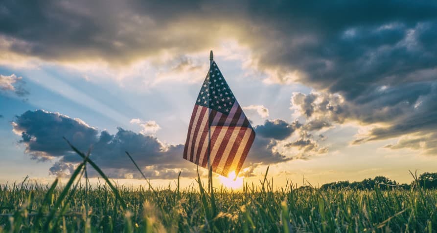 american flag over grass in sunset