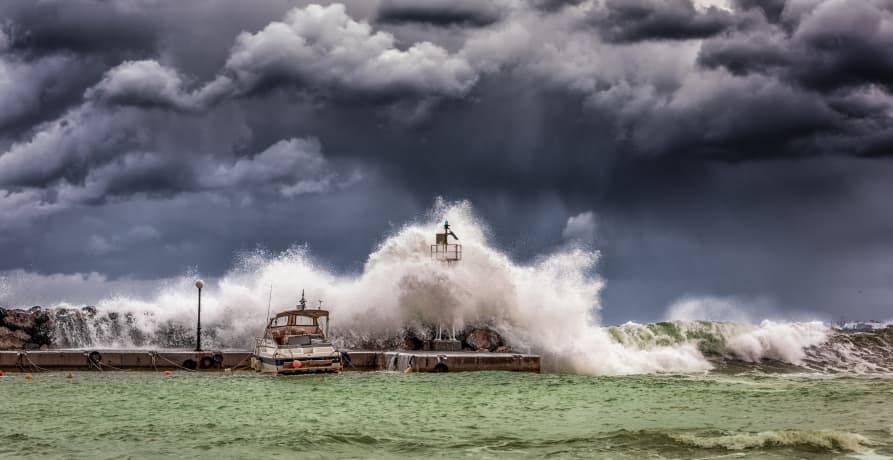 sea storm with large wave breaking over a harbour