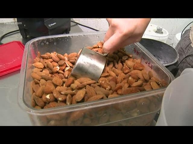 someone filling measuring cup with almonds