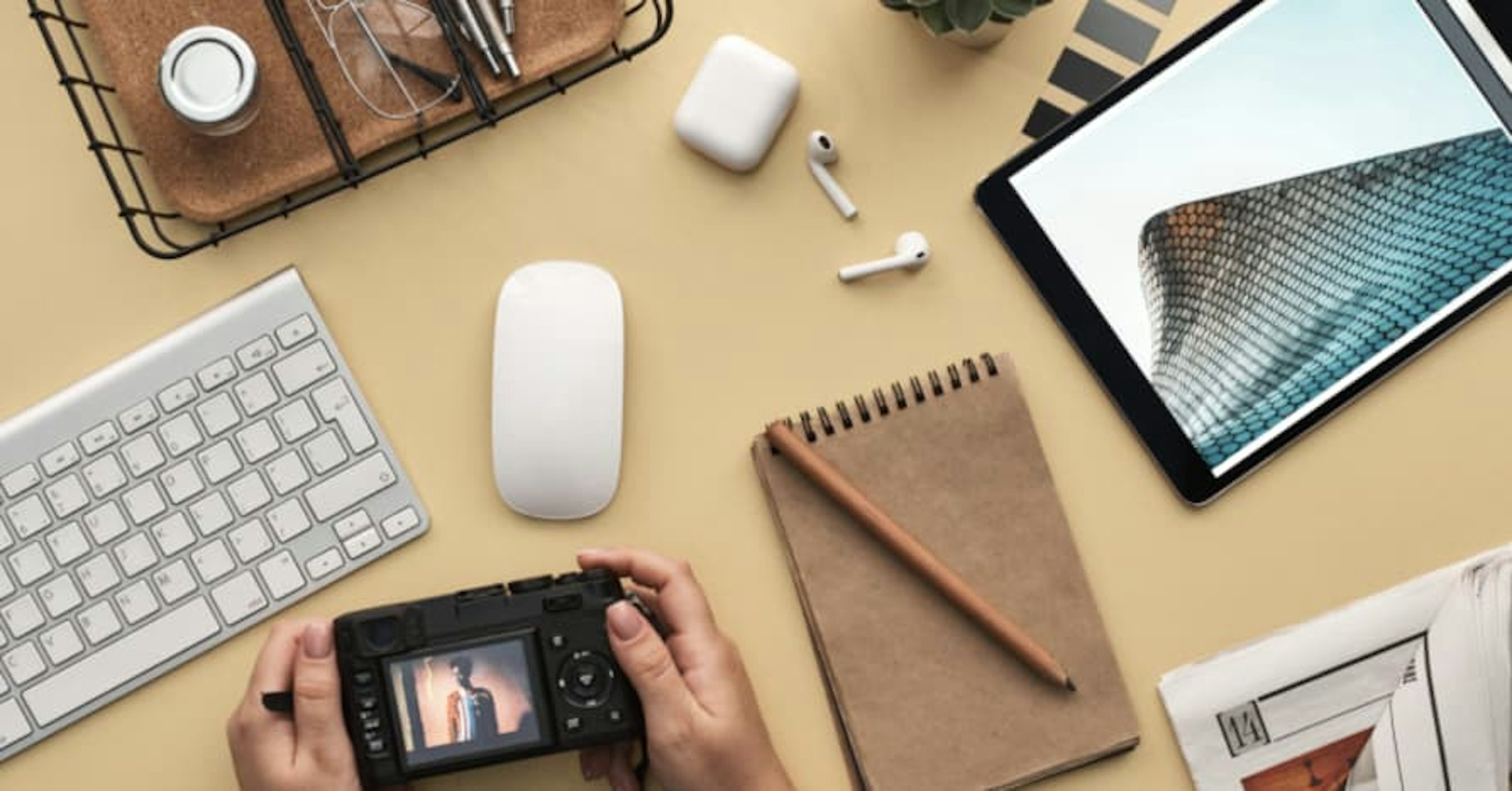persons desk with airbods, phone, notebook, and tablet