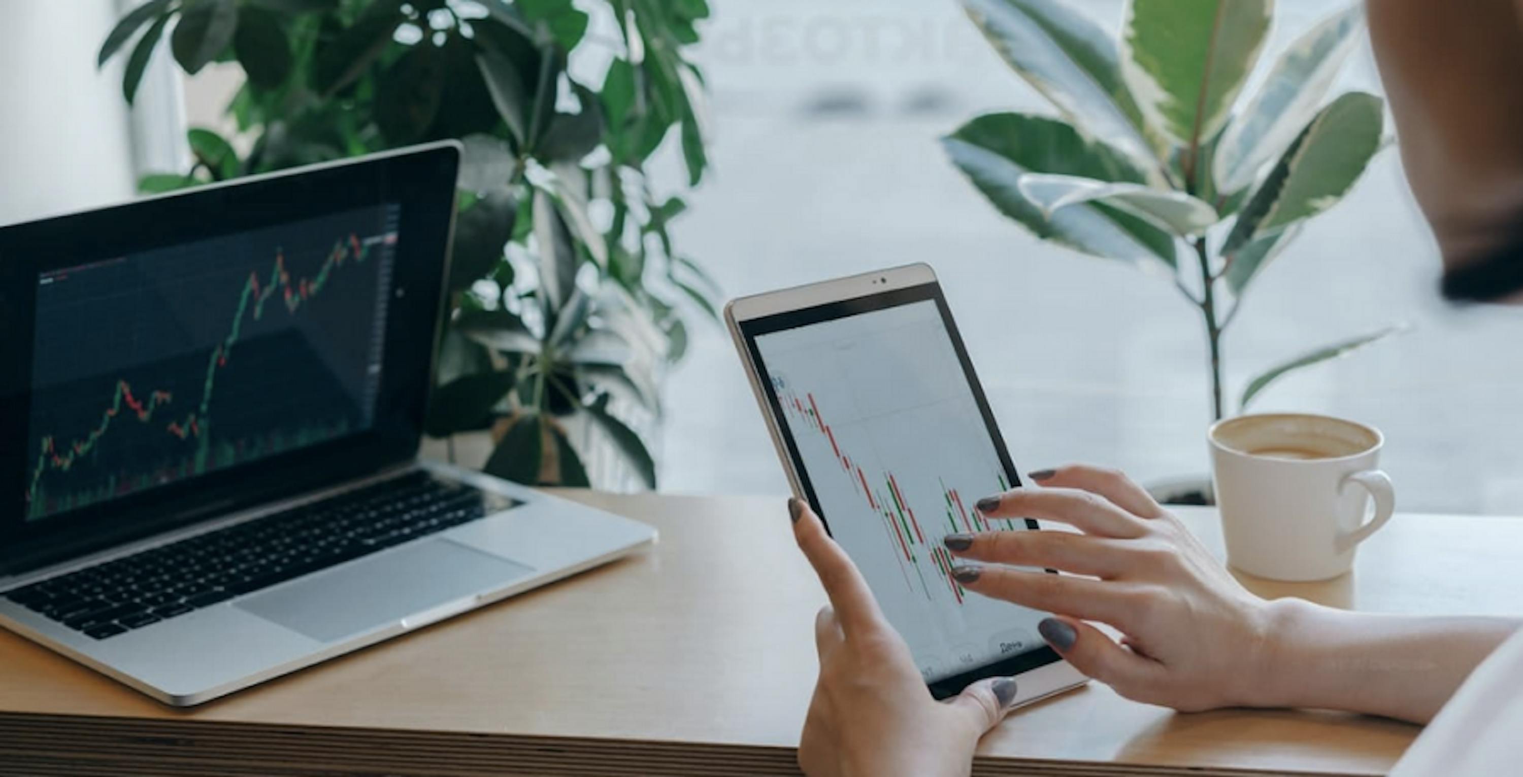 macbook and ipad with data, coffee, and green plants 