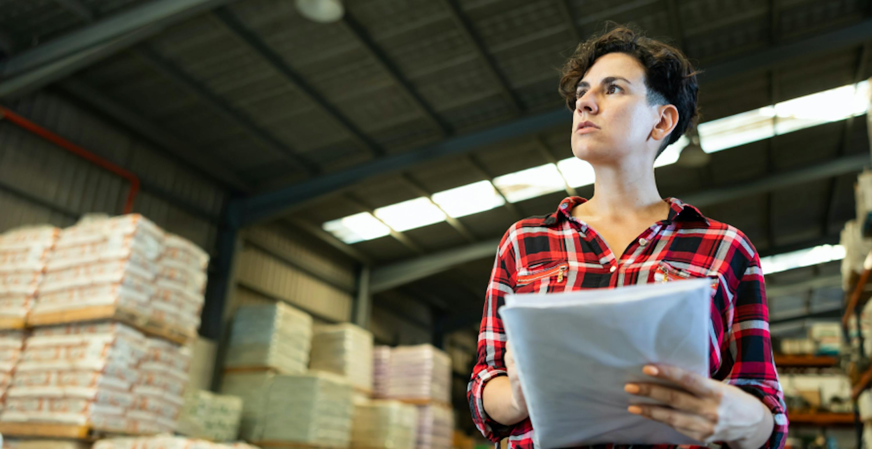 Une femme dans un entrepôt tenant des documents à la main