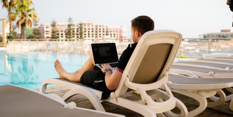 person working on laptop poolside