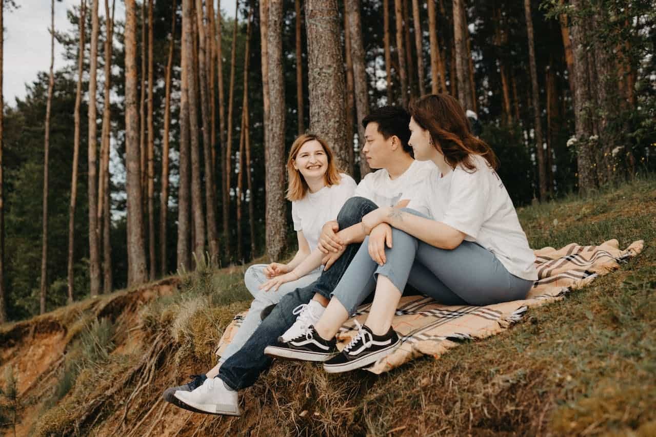 Amis assis sur une couverture dans la forêt