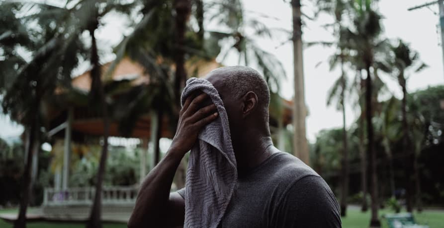 man wiping sweat from his face with towel