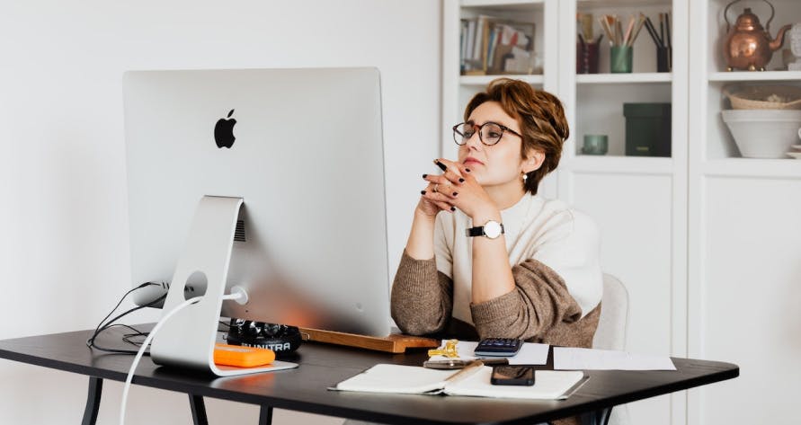 une femme réfléchissant devant son ordinateur