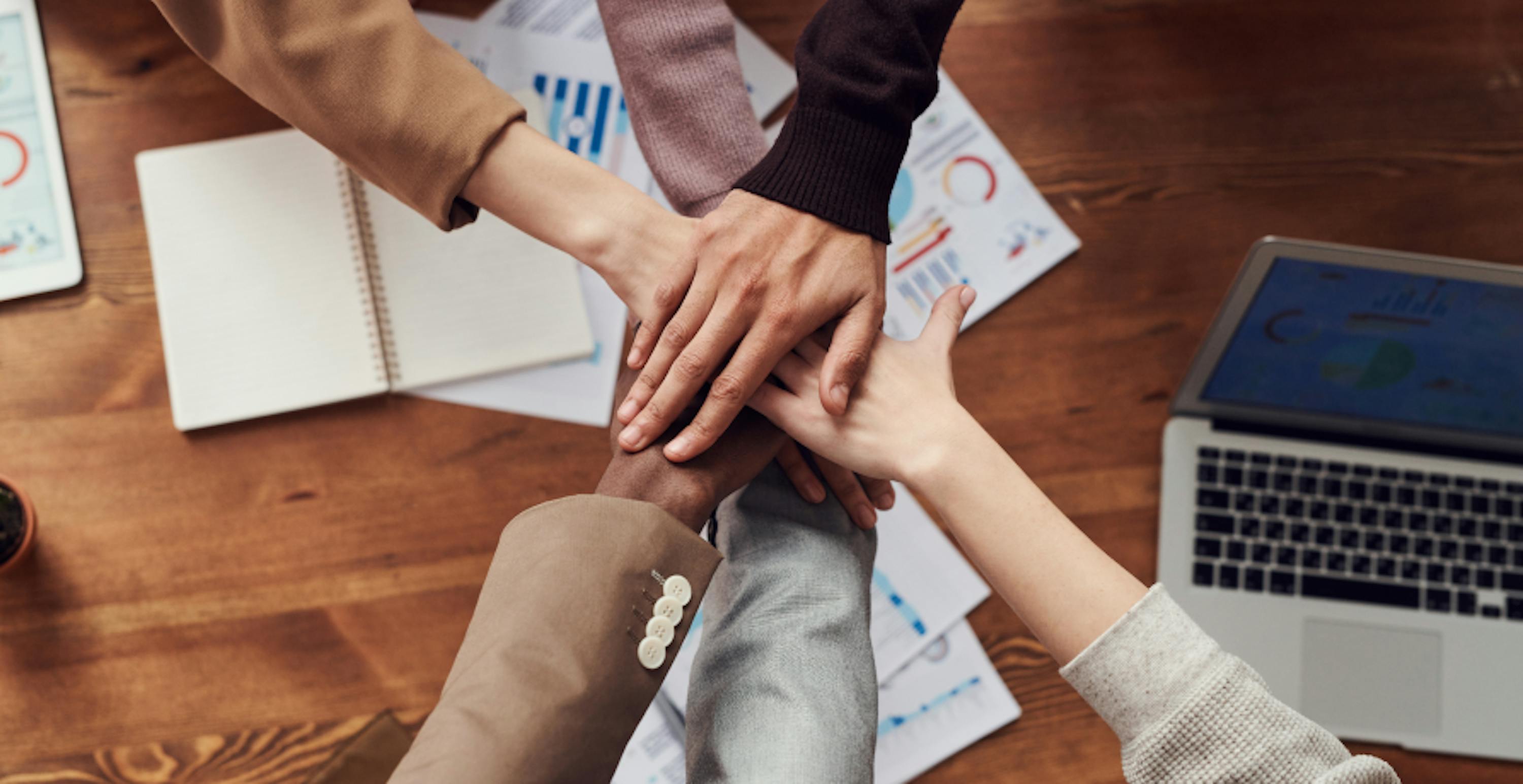 employees giving high five over office desk 