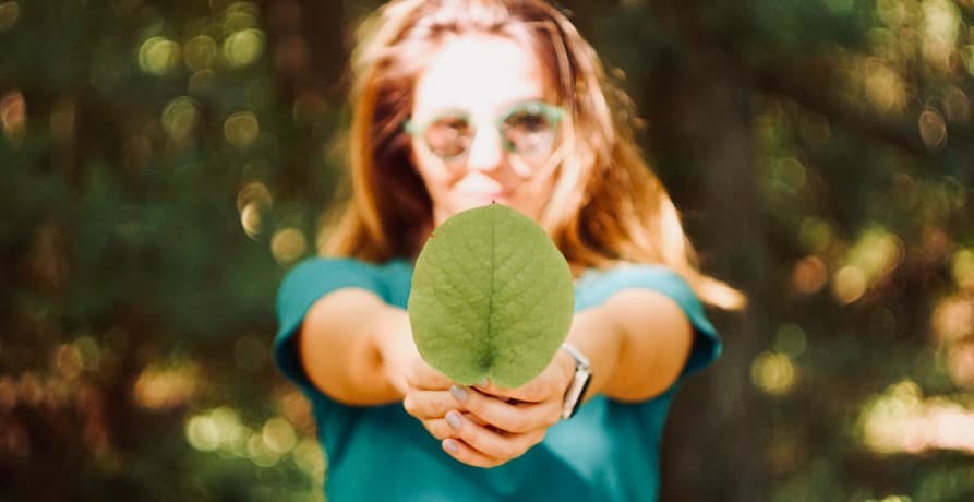 girl holding giant leaf in the sun