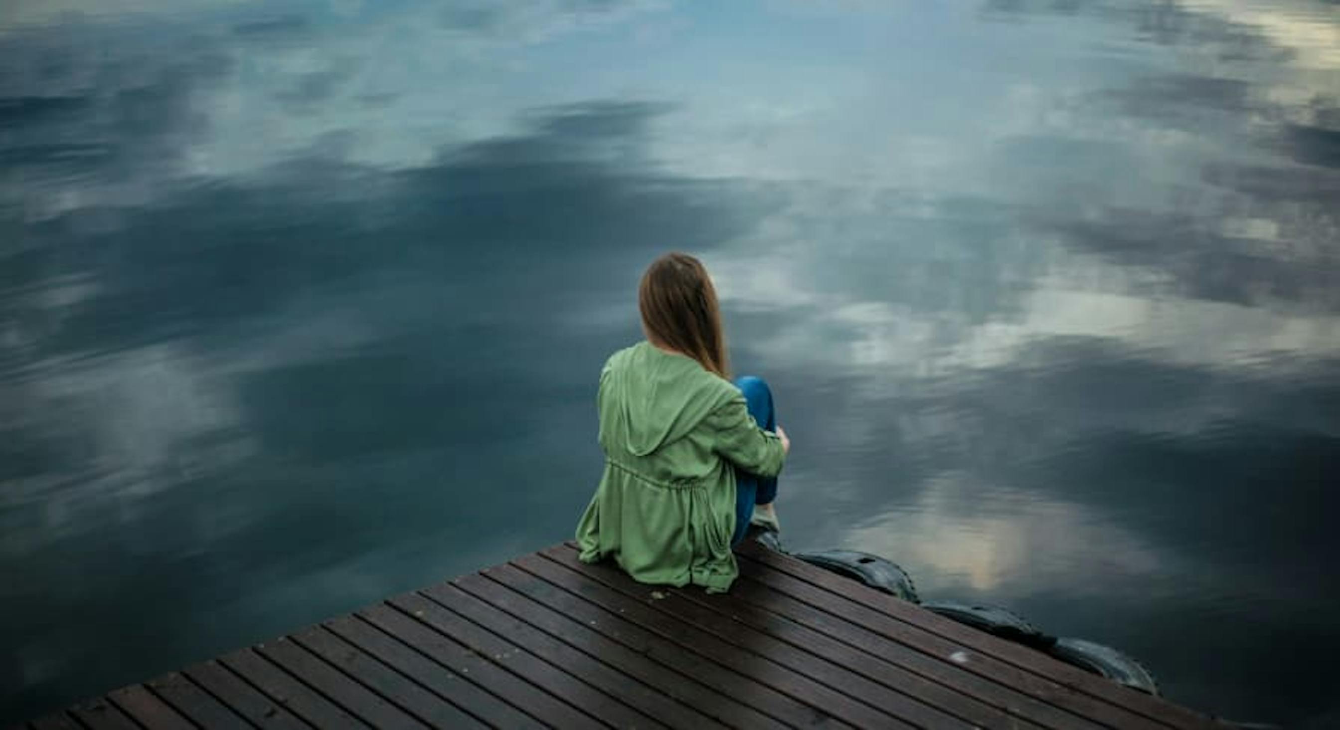 person standing near edge of river alone 