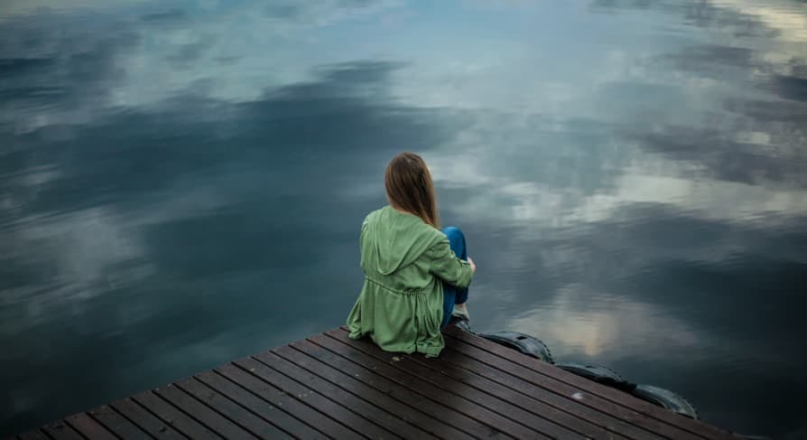 person standing near edge of river alone