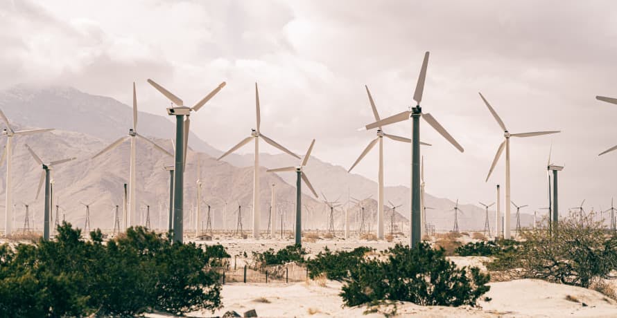 wind turbines in front of cloudy mountains