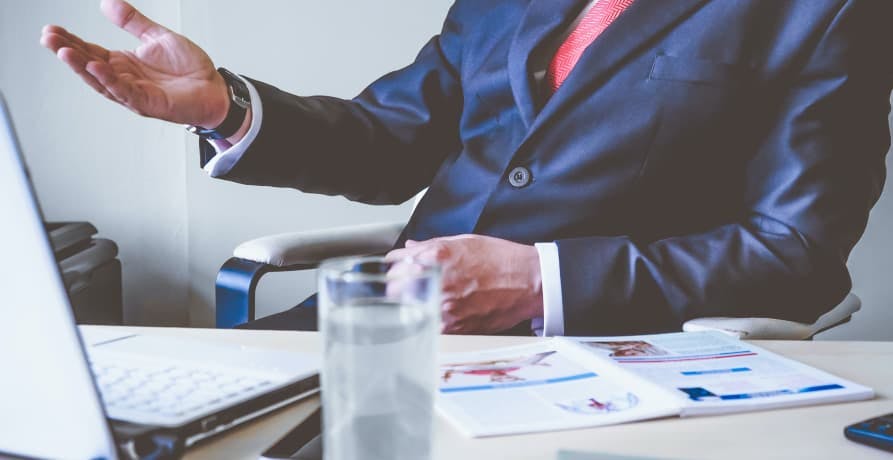 man in suit with lots of data reports on his work desk