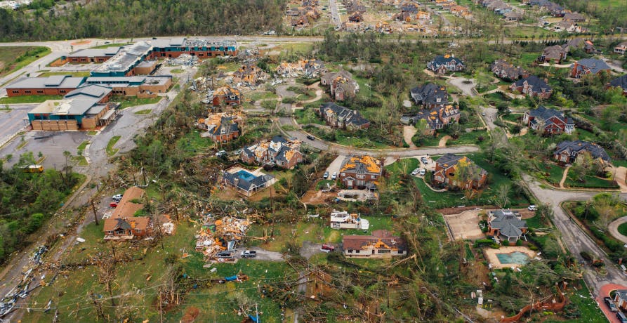 Village houses with damaged roofs and uprooted trees