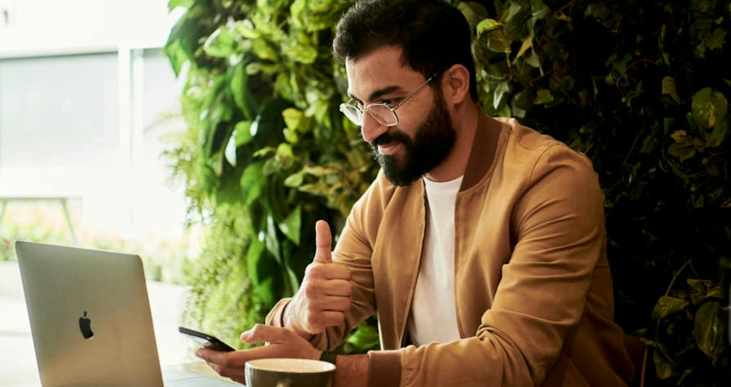 guy working on laptop in front of large green bush