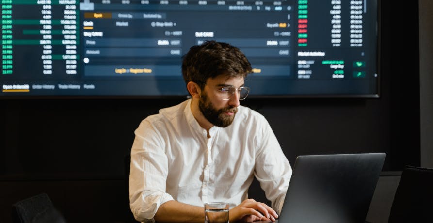 trader sitting in front of screen with investment data