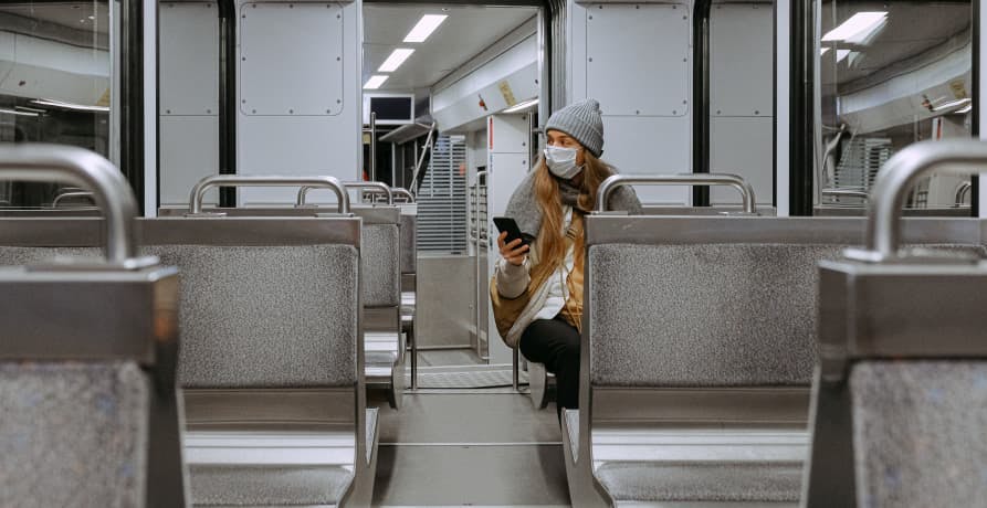 person sitting alone on metro with mask during pandemic