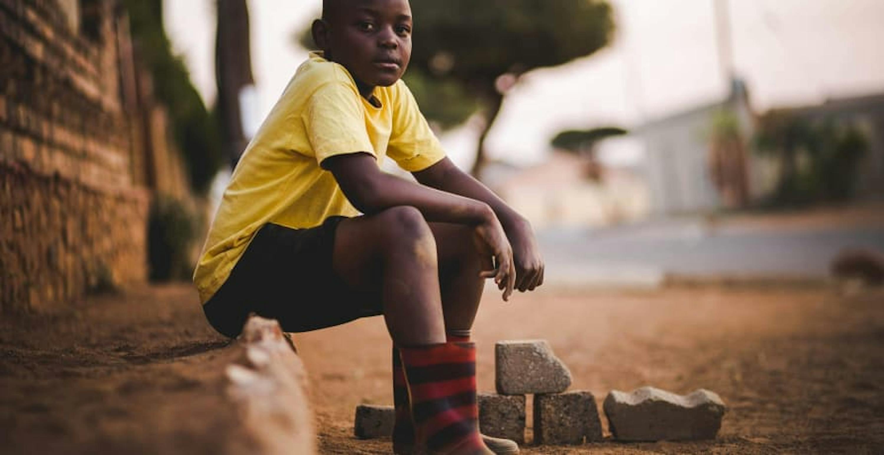 child sitting on pavement looking at the camera