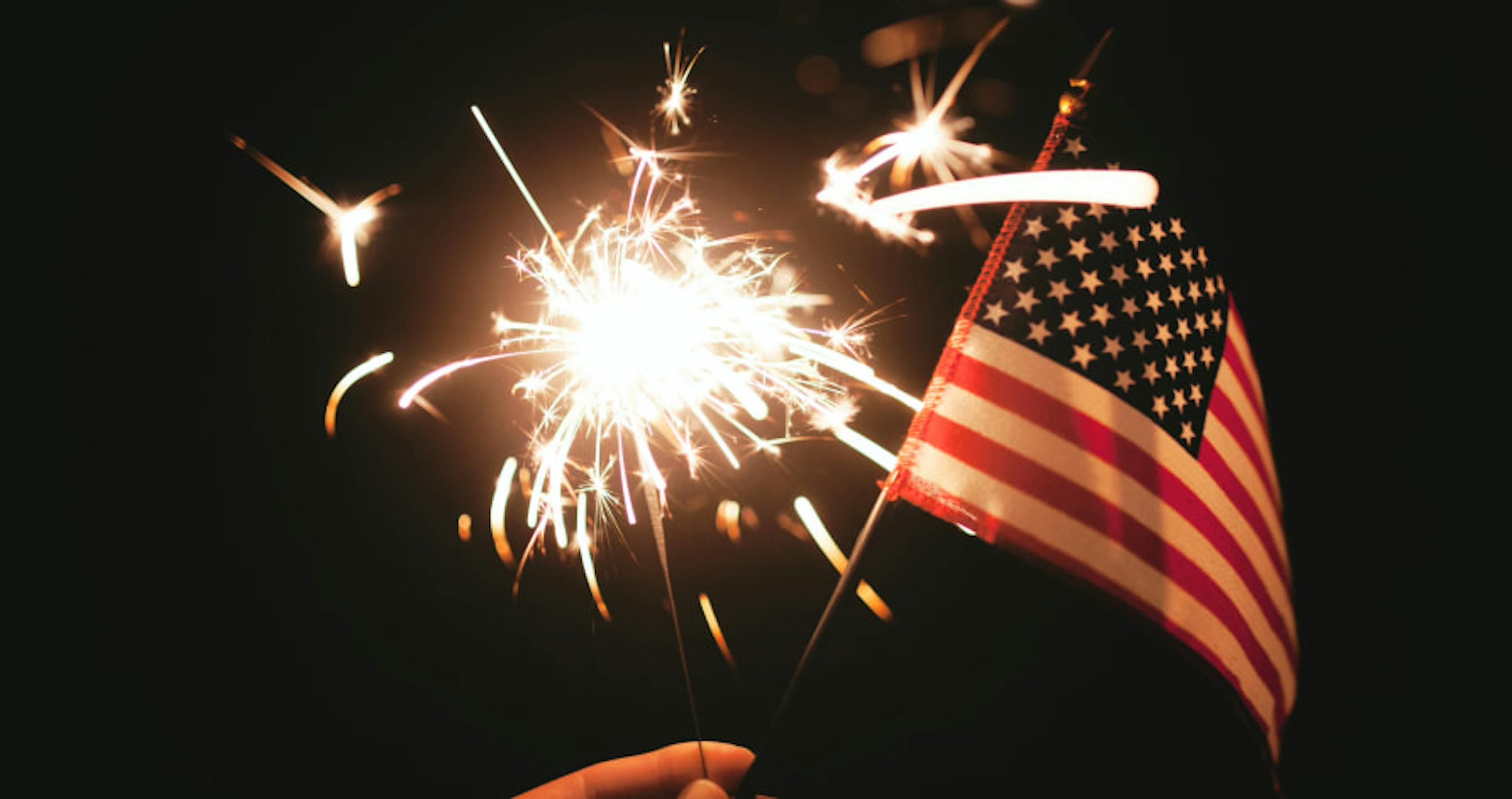 foruth of july fireworks and flag against dark sky