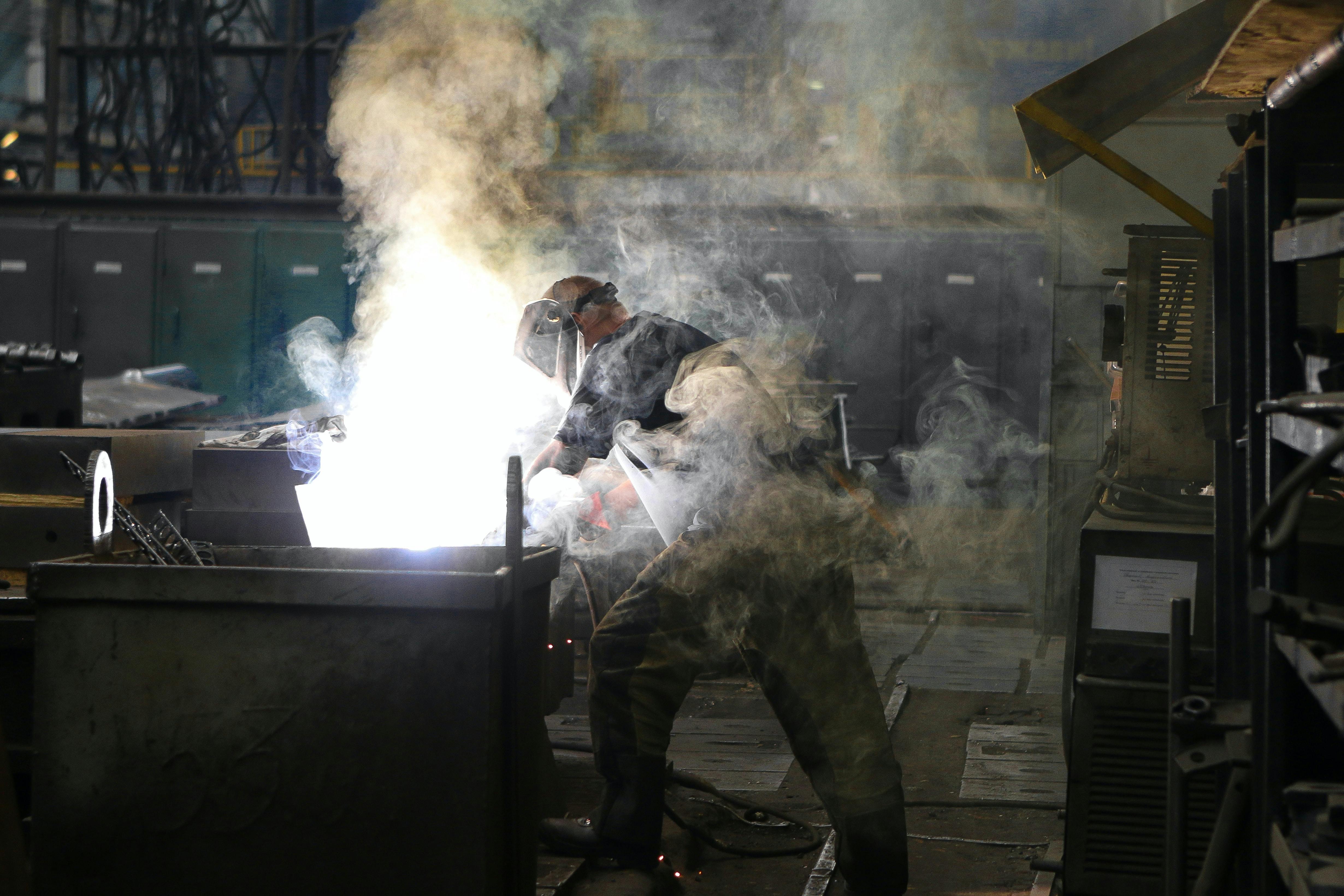 man working inside factory with lots of smoke