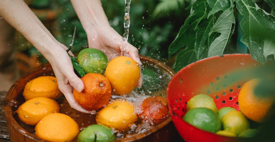 person washing fruits in bowl