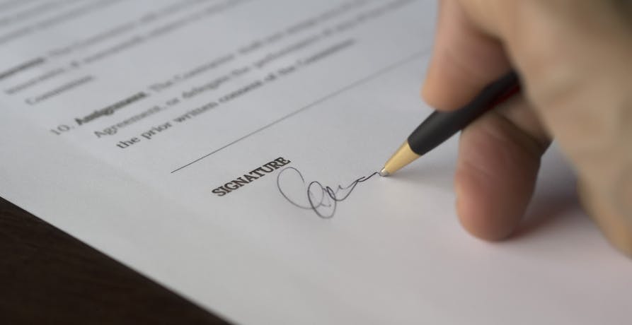 une personne apposant sa signature sur un document