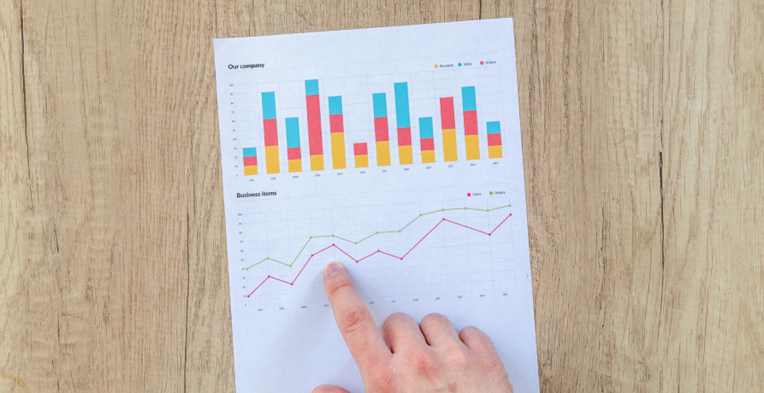 une main pointant du doigt une feuille avec des statistiques en hausse