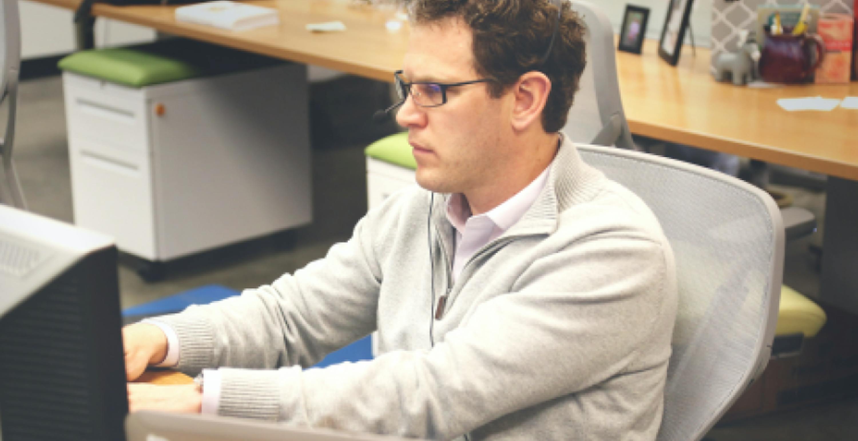 un homme à lunettes tapant sur le clavier de son ordinateur