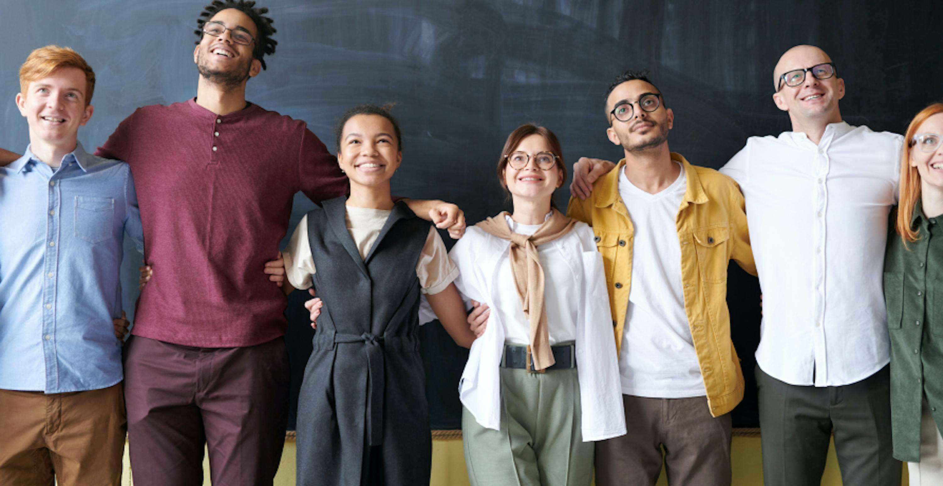 happy employees standing with their arm around each other smiling