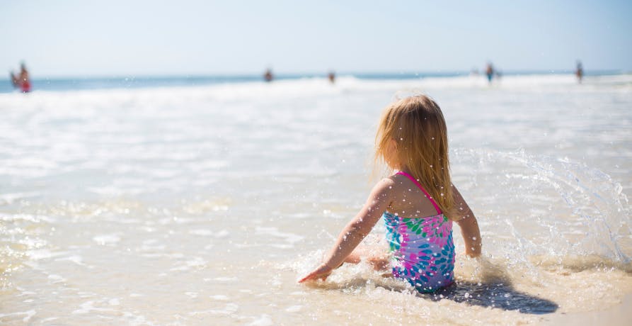 child at beach sitting in the water